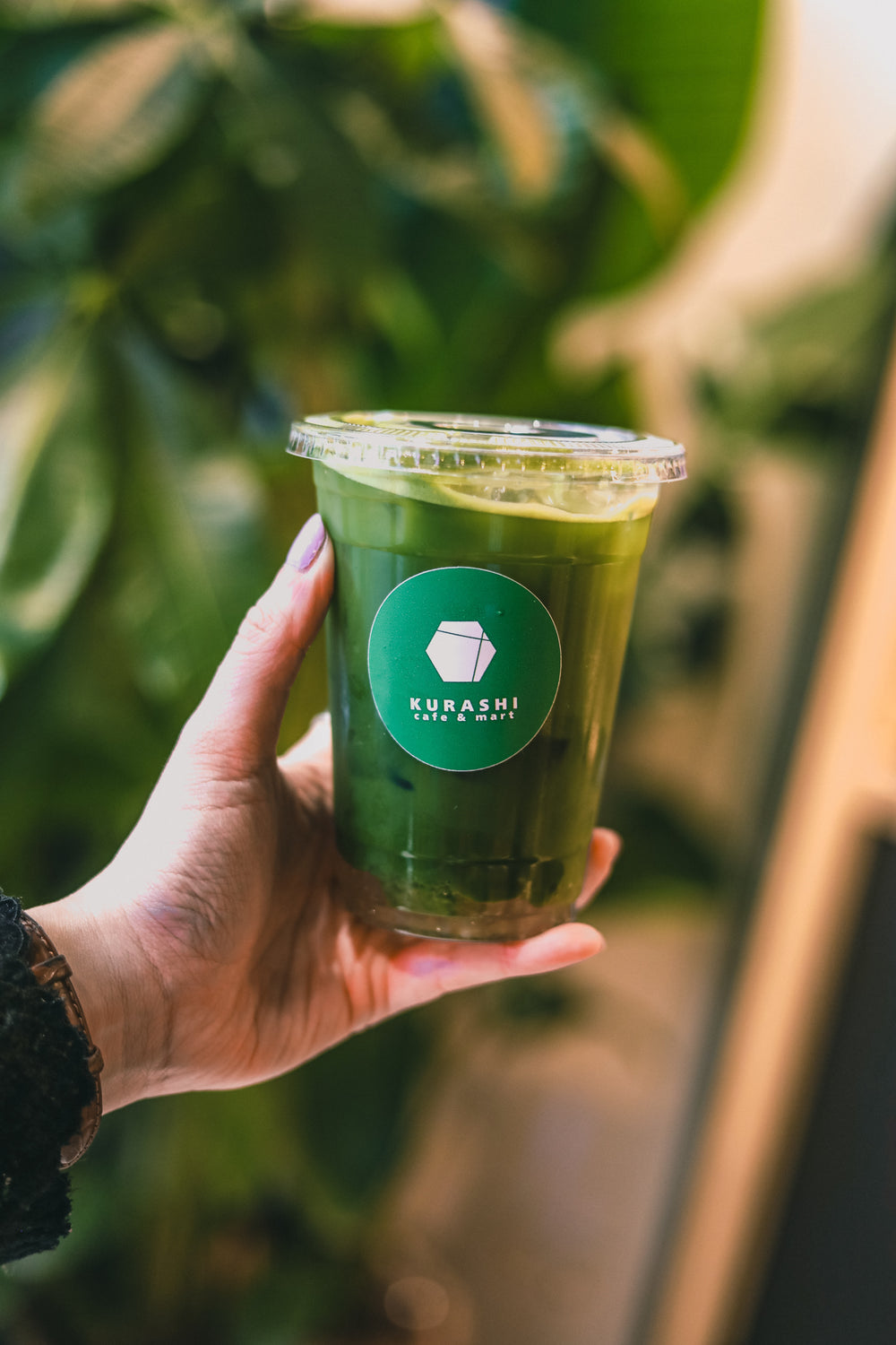 Un matcha glacé tenu à la main devant le comptoir
