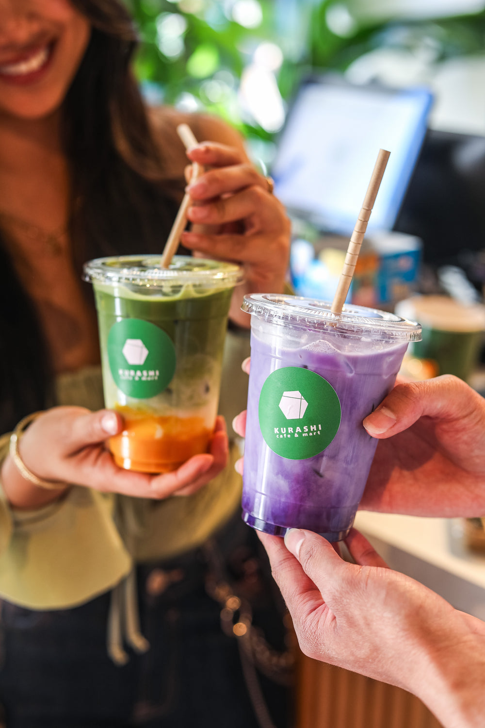 Un latte à l'igname violette et un matcha glacé, tenus côte à côte